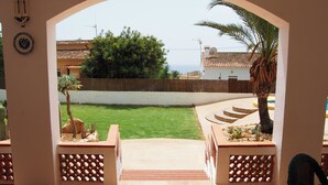 A view through an archway into a courtyard with a lawn, palm tree, and a small garden with cacti and succulents. - See view villa with pool and big garden. (MORAIRA, (ALICANTE) ESPAÑA)