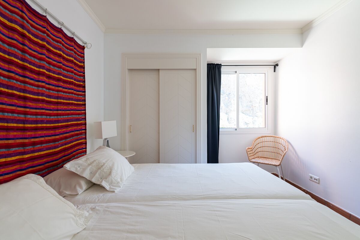 Une chambre avec deux lits, une fenêtre donnant sur un beau paysage, une chaise et une porte.