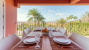 Mesa de comedor para cuatro con vista a palmeras y cielo despejado.
