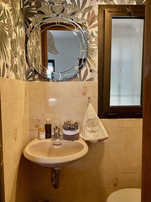 Une salle de bain avec un lavabo, un miroir et une fenêtre.