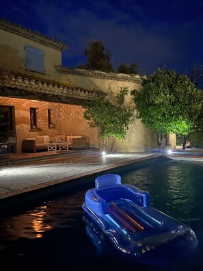 A pool area with a lounge chair and a small inflatable boat.