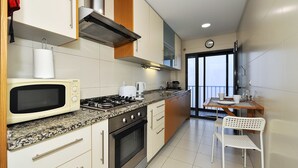 Een moderne keuken met een magnetron, fornuis en kasten.