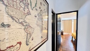 Ein Flur mit einer großen Weltkarte an der Wand, der zu einem Zimmer mit einem Bett und Vorhängen führt.
