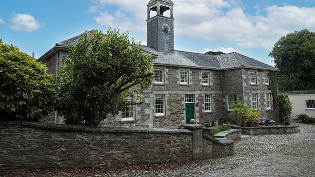 A stone building with a clock tower, multiple windows, and a green door. - The Clock House at Heligan Gardens (Pentewan)