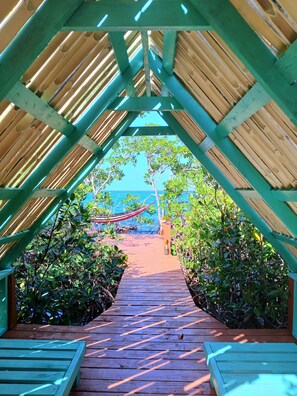 A wooden pathway leading to a beach under a green roof structure. - Are you in need of ADVENTURE? (Stann Creek)