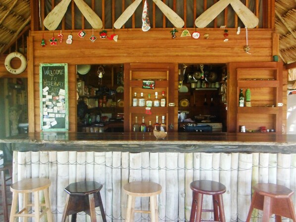 A rustic bar area with wooden shelves, a welcome sign, and various bottles. - Are you in need of ADVENTURE? (Stann Creek)
