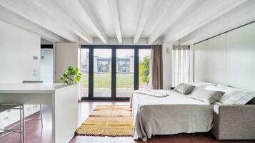 Ein modernes Schlafzimmer mit Bett, Schreibtisch und Blick ins Freie.