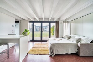 A modern bedroom with a bed, a desk, and a view of the outdoors.