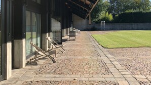 A covered outdoor area with a brick pathway leading to a seating area with tables and chairs.