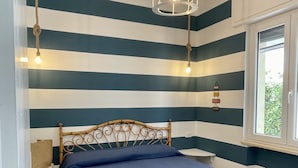 Una stanza con un letto, una finestra e una parete a righe orizzontali.