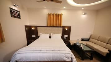 A neatly arranged hotel room with a large bed, a sofa, and a coffee table.