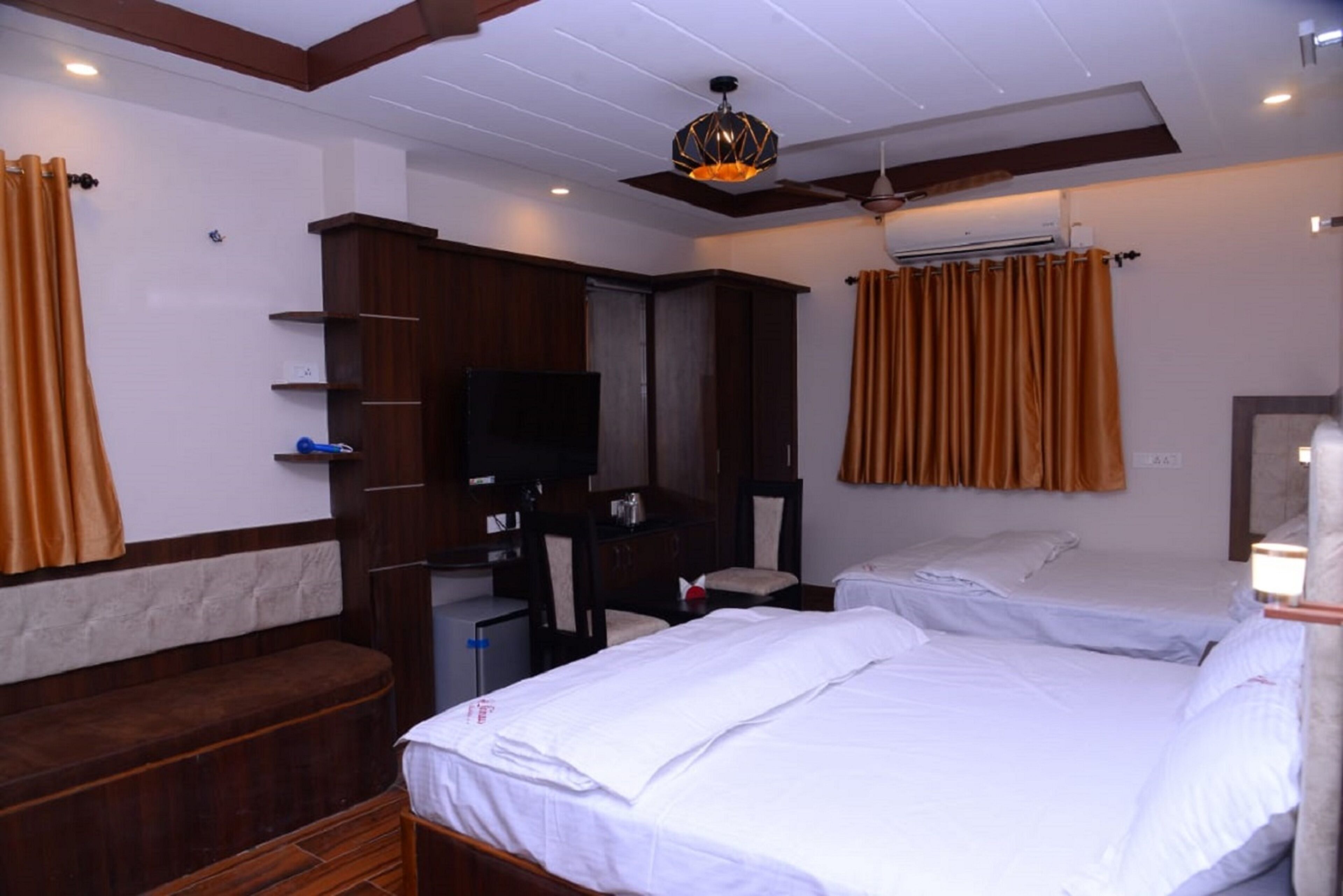 A hotel room with a bed, a desk, a chair, a television, and a ceiling fan.