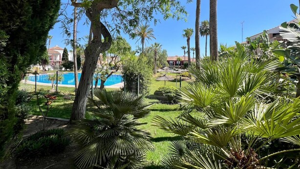 Une piscine entourée de palmiers et un bâtiment avec un toit rouge.