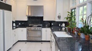 A modern kitchen with white cabinets, a stainless steel range, and a black countertop.