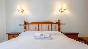 A neatly made bed with a wooden headboard, two bedside tables, and wall-mounted lamps.