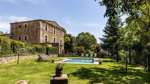 A stone building with a swimming pool, surrounded by a well-maintained lawn and trees. - More Riera SPECTACULAR FARMHOUSE near Besalú for 13 people (Maià de Montcal)
