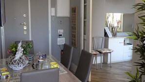 Ein stilvoller Essbereich mit Holztisch und -stühlen, einer Pendelleuchte und Blick in die Küche.