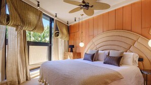 A bedroom with a large bed, a ceiling fan, wooden panel walls, and a view of greenery outside. - Hot Tub, sea, wifi pro, gas barbecue, garden, 11 (San Miguel de Abona)