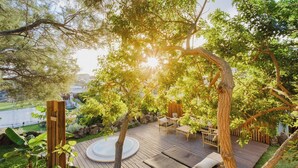 A wooden deck with outdoor furniture, surrounded by trees and a view of a body of water. - Hot Tub, sea, wifi pro, gas barbecue, garden, 11 (San Miguel de Abona)
