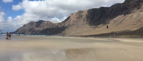 Een strand met een heldere lucht en bergen op de achtergrond.