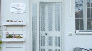 A white door with vertical lines, a sign above it, and a window to the right.