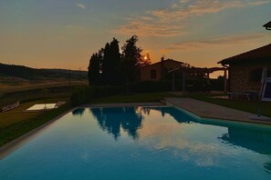 A rectangular swimming pool with a clear view of the surrounding landscape, including a house and trees.