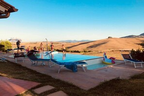 An outdoor swimming pool with lounge chairs and a view of rolling hills.