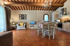 Ein gemütliches Wohnzimmer mit einem Esstisch, Stühlen, einer Couch und einem Fernseher.