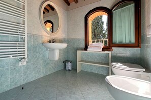 A bathroom with a white sink, a mirror, a window, and a toilet.