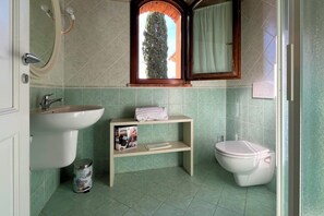 Un baño con lavamanos, inodoro y una repisa con una revista.