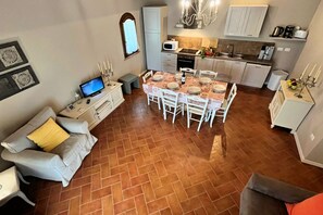 A compact living space with a dining area, kitchenette, and a TV.