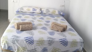 A bed with a leaf-patterned bedspread, two pillows, and two rolled towels. - SES SIVINES 3hab. PRIVATE POOL (Ciutadela)