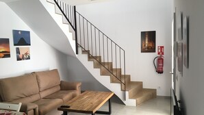 A modern living room with a staircase, a sofa, a coffee table, and a fire extinguisher. - SES SIVINES 3hab. PRIVATE POOL (Ciutadela)