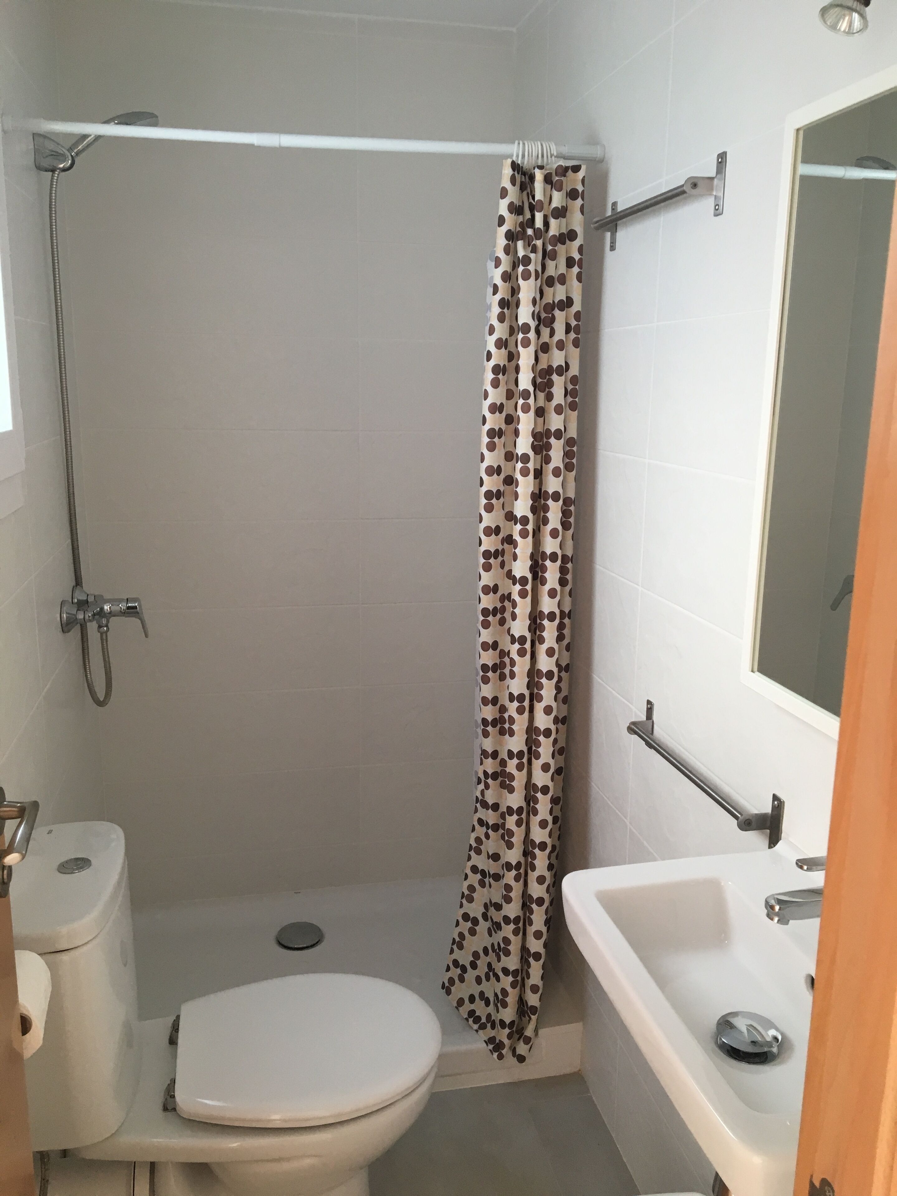 A small bathroom with a toilet, shower, and sink.