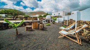 A patio with a wooden table, chairs, and a small tree. -  Peace in the countryside 1 km from the beach, magnificent views, bbq and free wifi (Tabayesco)