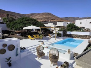 Une piscine sur le toit, dotĂ©e de chaises longues, dâune pergola et offrant une vue sur les montagnes.