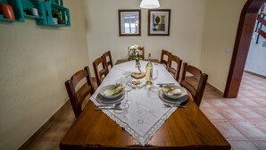 A dining table set with plates, glasses, and a centerpiece. There are chairs around the table, and a shelf with items on the left. -  Peace in the countryside 1 km from the beach, magnificent views, bbq and free wifi (Tabayesco)