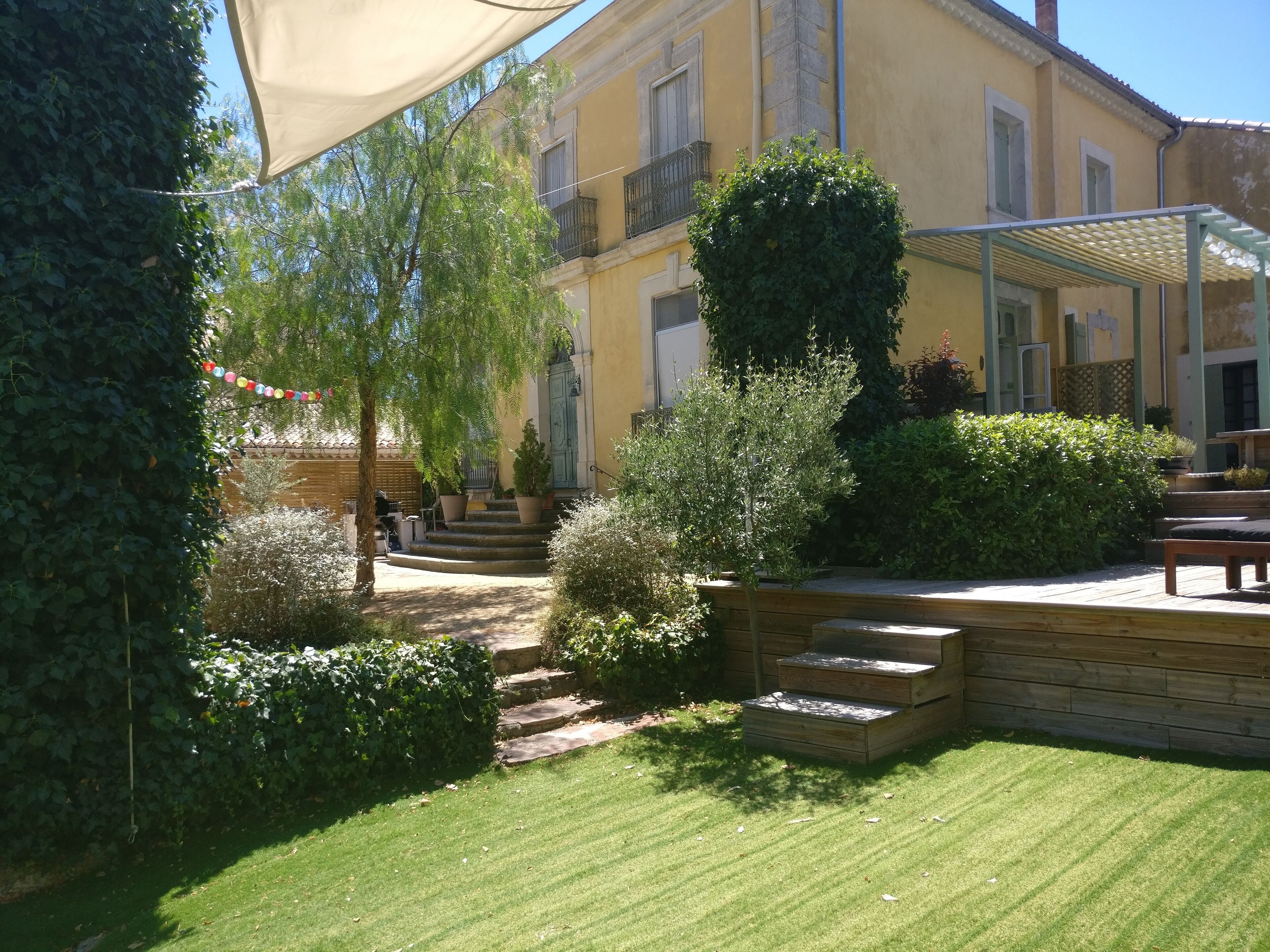 A courtyard with a yellow building, stone steps, and a wooden deck.