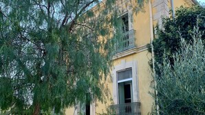 A two-story building with a yellow facade, a balcony, and a staircase leading to the entrance. - Charming wine maker house with generous surfaces, garden and pool in Languedoc (Murviel-Lès-Béziers)