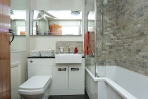 A modern bathroom with a white toilet, a sink, and a shower. - Annie's Cottage.  A pretty chocolate box style cottage with lots of character. (Kent)