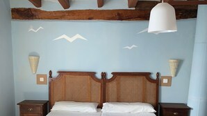 A double bed with a wooden headboard, two bedside tables, a hanging light fixture, and a small table with a folded towel. - Self catering cottage Laguna Herrera for 14 people (Cuéllar)