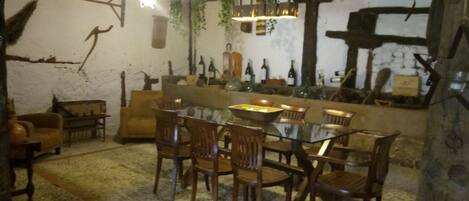 Un comedor rústico con una mesa de vidrio rodeada de sillas de madera, un sofá y una pequeña mesita auxiliar.