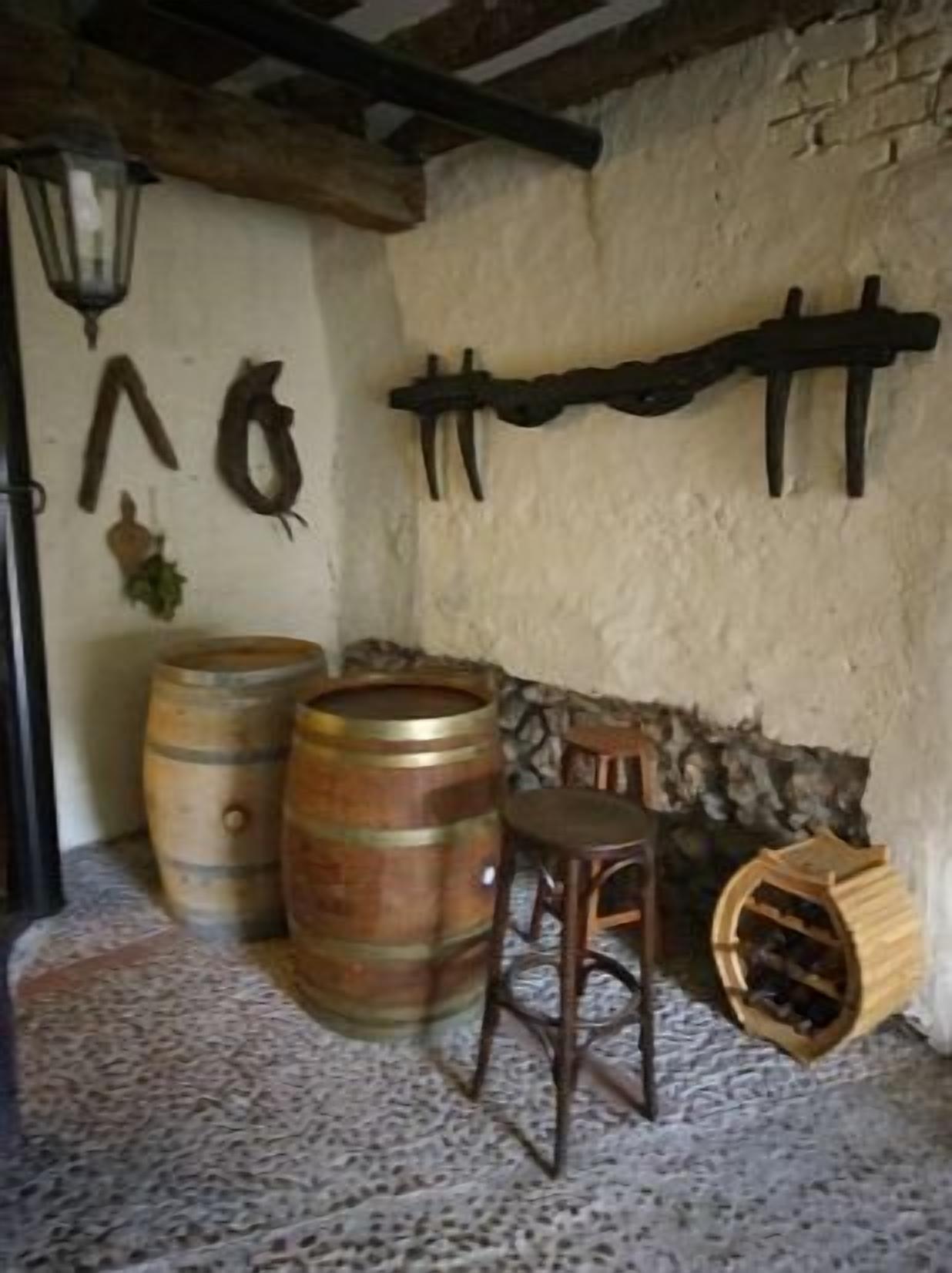 A rustic room with wooden barrels, a wooden chair, and a stone wall.