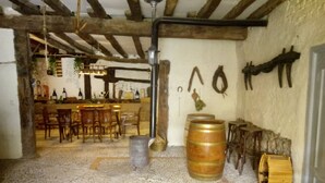 A rustic interior with exposed wooden beams, a bar area with bottles, and a stone floor. - Self catering cottage Laguna Herrera for 14 people (Cuéllar)