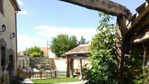 A courtyard with stone flooring, a wooden pergola, and a small garden area. - Self catering cottage Laguna Herrera for 14 people (Cuéllar)