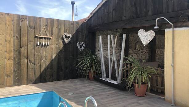 A backyard with a swimming pool, wooden fence, decorative heart-shaped items, and potted plants. - Self catering cottage Laguna Herrera for 14 people (Cuéllar)