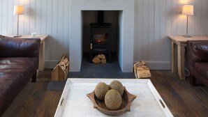 Een gezellige woonkamer met een open haard, leren banken, een bijzettafeltje met decoratieve ballen en twee lampen.