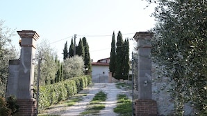 A gated entrance with a gravel path leading to a building with a red-tiled roof.