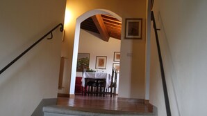 A staircase leading to a dining area with wooden beams and framed artwork on the walls.