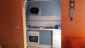 A compact kitchen with blue cabinets, a white stove, and a sink. - Beautiful duplex, ideal for families, near the sea (Gran Alacant)